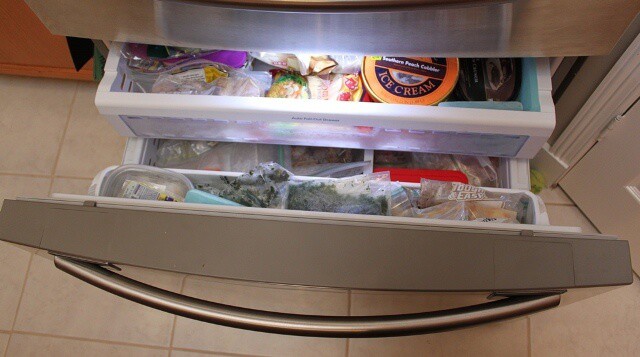 This is my freezer below the refrigerator. It may not look super organized but it is! On the upper level is baked goods like tortillas and bagels, on the right is our ice cream stash. On the bottom, left side is nuts and some other leftover recipe ingredients. On the right is frozen fruit & veggies. In the upper edge, I have frozen herbs like parsley, cilantro, garlic, ginger, etc. and some homemade coffee creamer. I use my extra freezer to hold bigger items like meat or prepared meals ready to heat and eat.[/