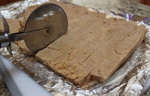 slicing pieces of peanut butter fudge with a pizza cutter