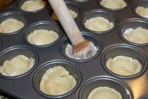 placing pecan tassies cookie dough into a tart pan