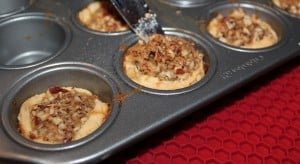 Pecan tassies being removed from the baking pan