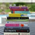 Stack of books on a table outside with text overlay at top.