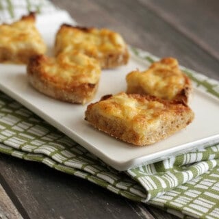 Image of triangular shaped Cheesy Crabmeat Canapes on a white plate on a green napkin