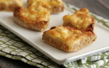 Image of triangular shaped Cheesy Crabmeat Canapes on a white plate on a green napkin