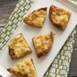 top view image of triangular shaped Cheesy Crabmeat Canapes on a white plate on a green napkin