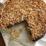 Top view of whole German Chocolate Sweet Cream Pie with slice taken out and pie plate on cloth towel.