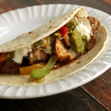 image of Simple Slowcooker Steak and Chicken Fajitas and bell peppers and onions in a tortilla