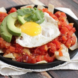 Simple Skillet Chilaquiles with eggs, avocados and tortilla in a mini skillet on a kitchen towel.