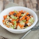 Chopped carrots and apples with raisins in a white bowl on burlap napkin.