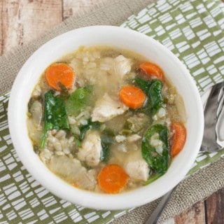 Top view image of bowl of Roasted Vegetable, Chicken and Rice Soup on a green napkin with spoon.