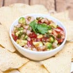 Shrimp avocado salsa in a white bowl with tortilla chips on plate.