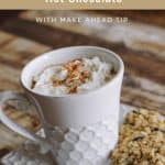 white mug with whipped cream and cinnamon sprinkled on top with oatmeal cookies on side plate with text overlay at top