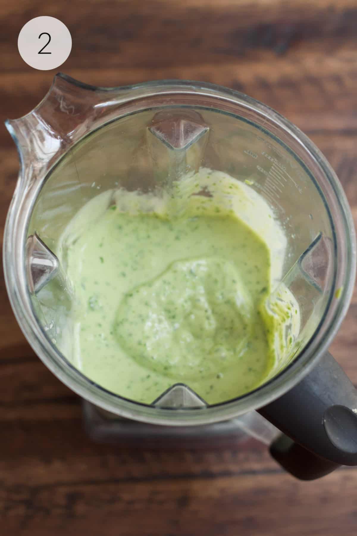 Blender jar with blended banana spinach and avocado smoothie.