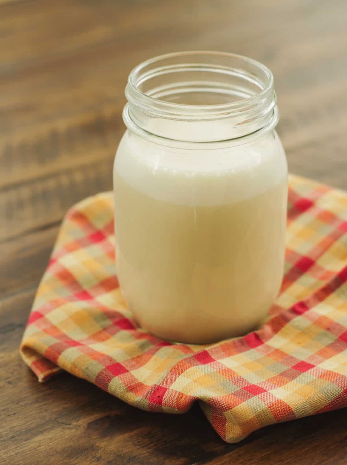 Glass jar with Cinnamon Vanilla Creamer on a multicolored napkin. 