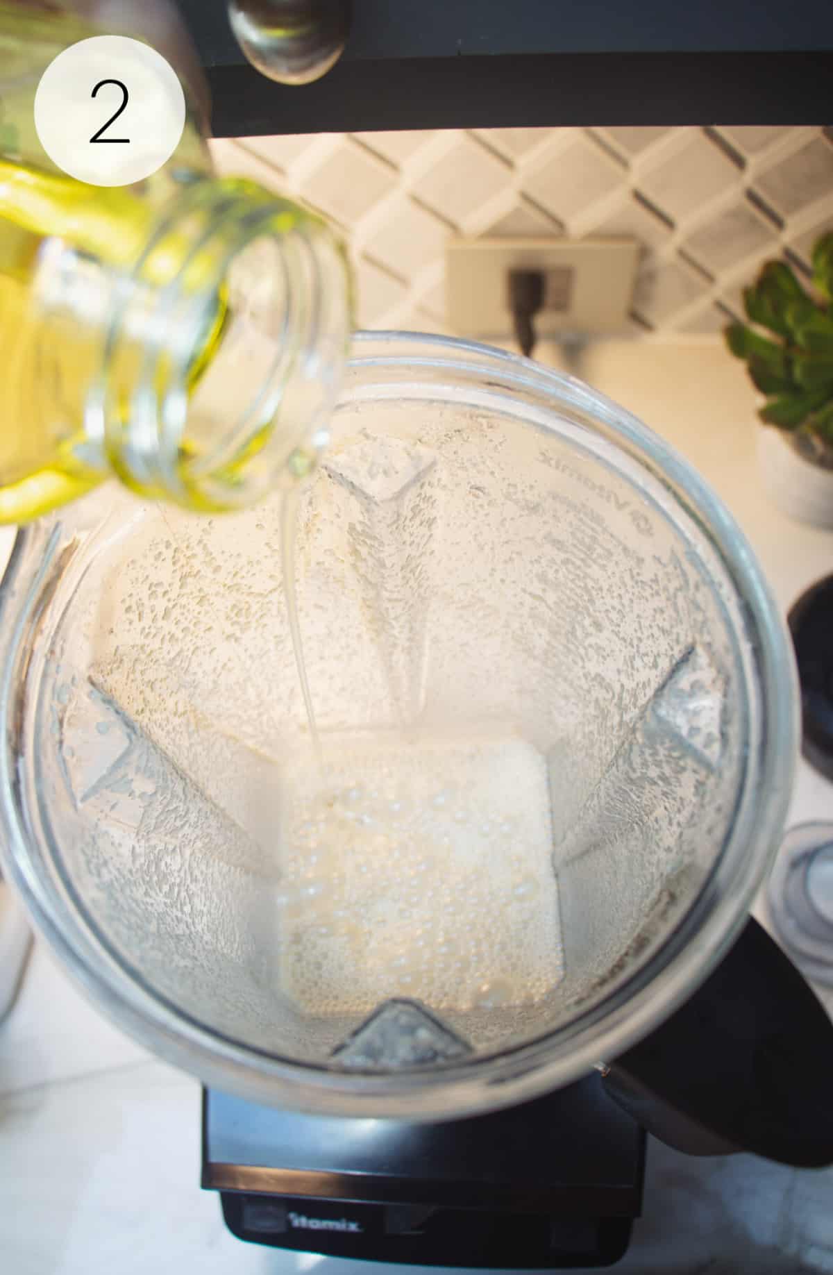 Pouring olive oil into a blender jar for making Vidalia Onion Dressing.