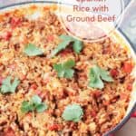 Spanish Rice with Ground Beef with cilantro leaves in a red cast iron skillet and small text overlay