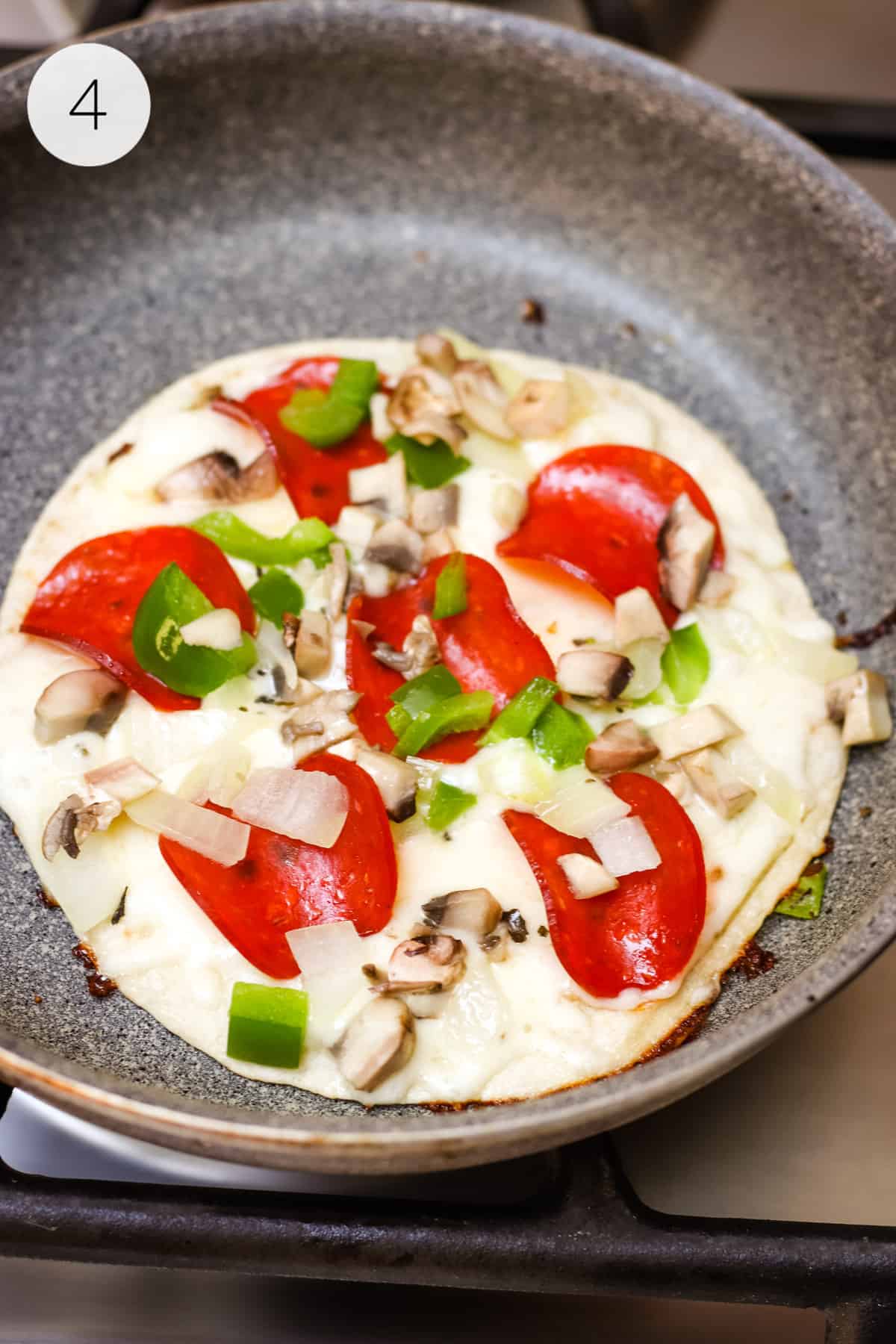 Flour tortilla layered with pepperoni, chopped green bell peppers, mushrooms and cheese in a pan.