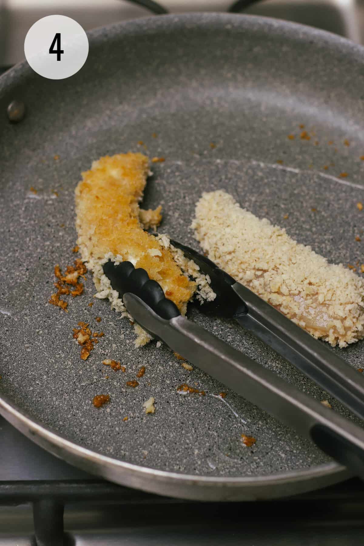 Breadcrumb coated chicken tenders being pan fried using tongs to flip. 