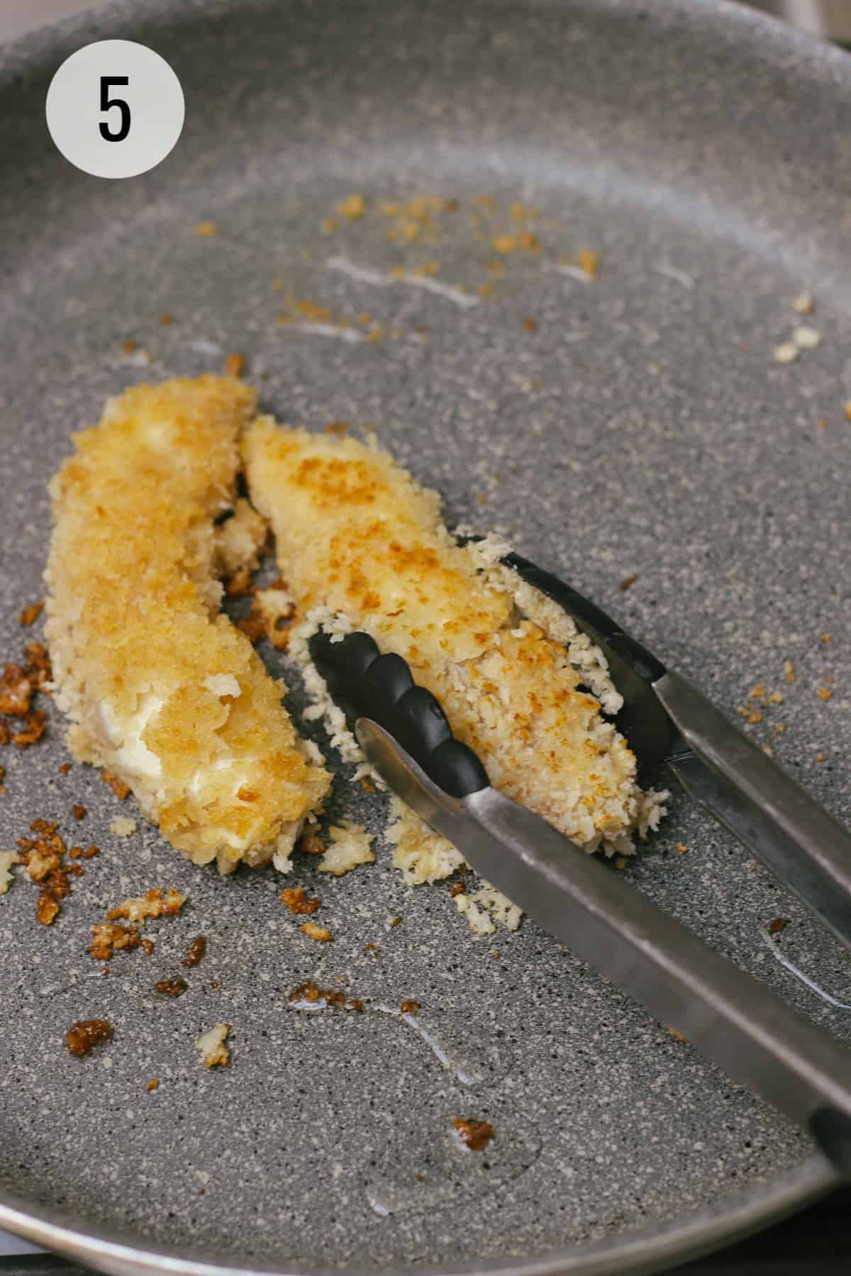 Pan frying breadcrumb coated chicken tenders in saute pan flipping with tongs. 