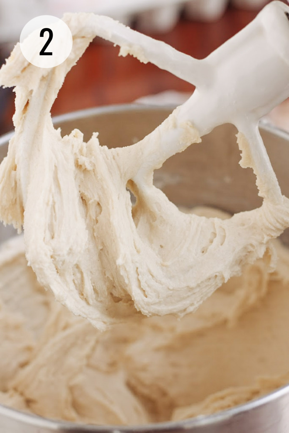 Pound cake batter on the paddle of a stand mixer with bowl of batter in background.