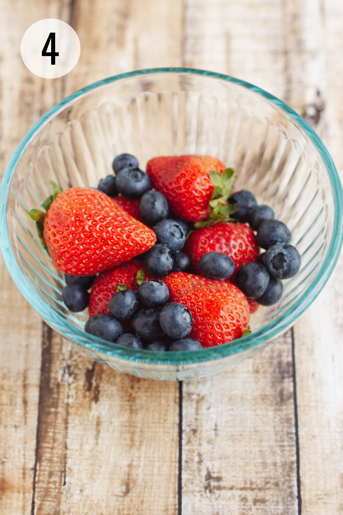 Glass bowl of fresh strawberries and blueberries. 