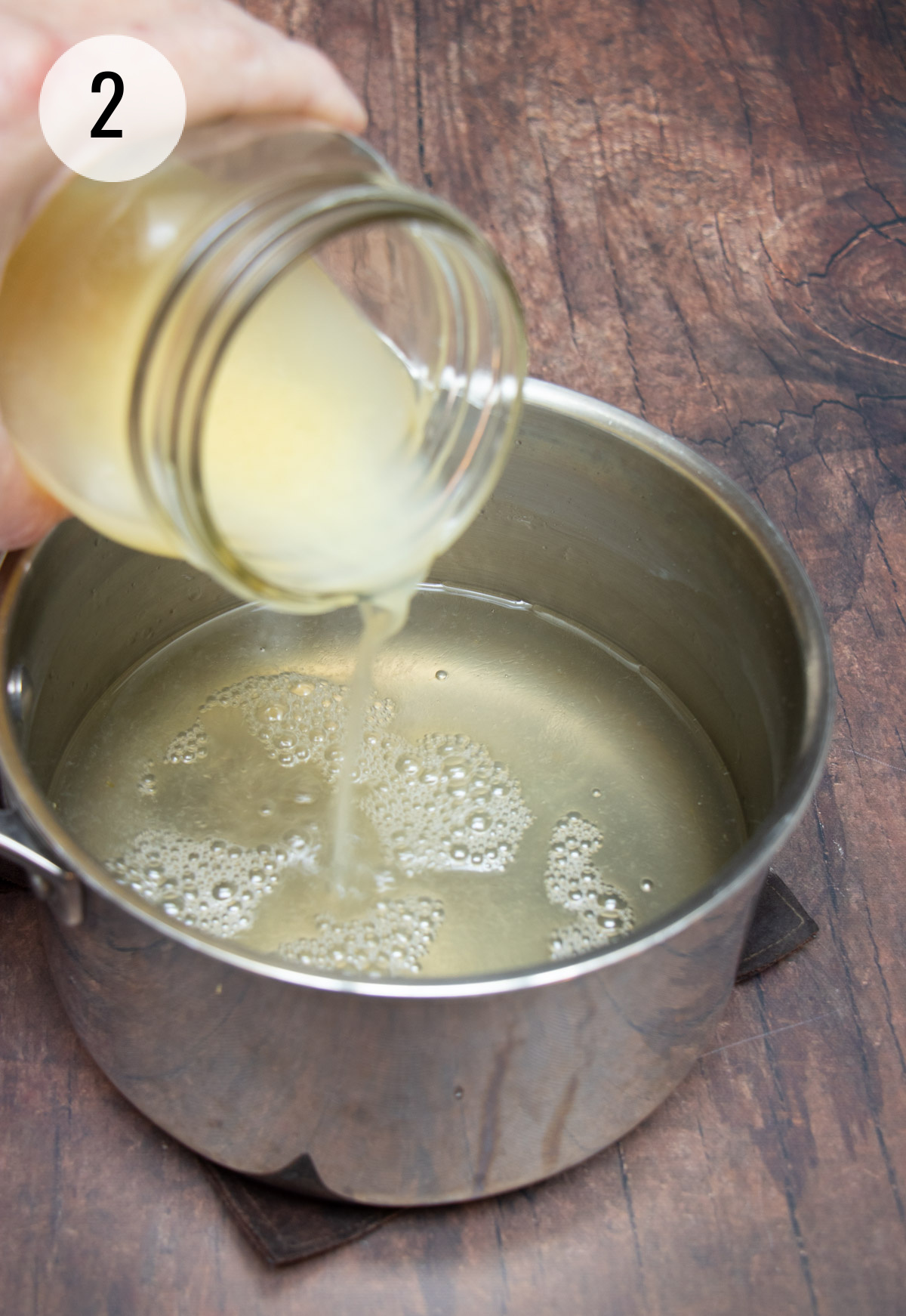 Pouring lemon juice into silver saucepan with simple syrup in it for fresh lemonade. 