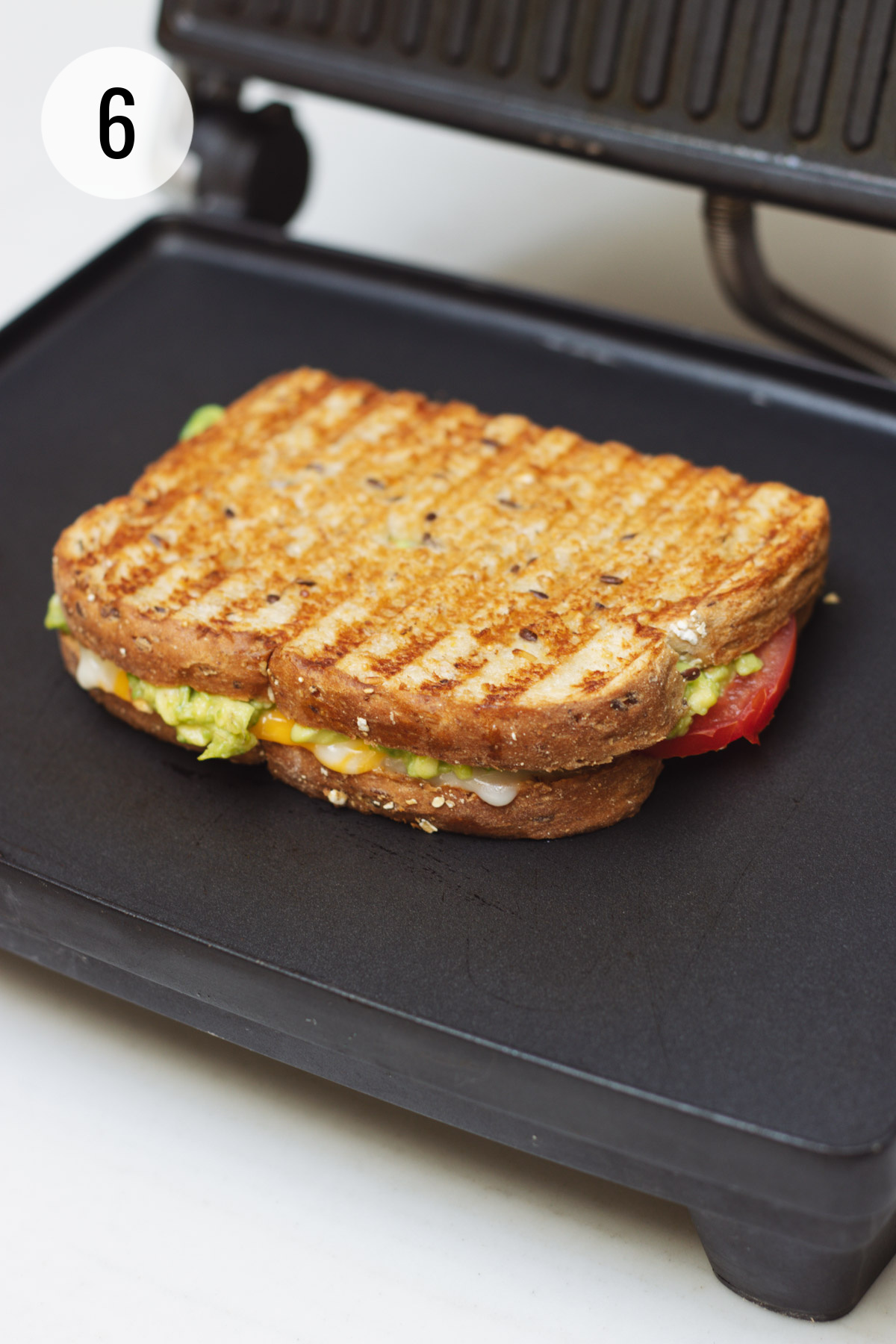 Grilled tomato and avocado grilled cheese sandwich on a panini maker. 