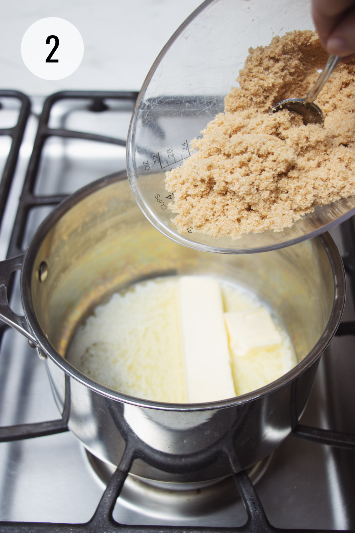 Brown sugar being scooped into sauce pan with melted butter. 