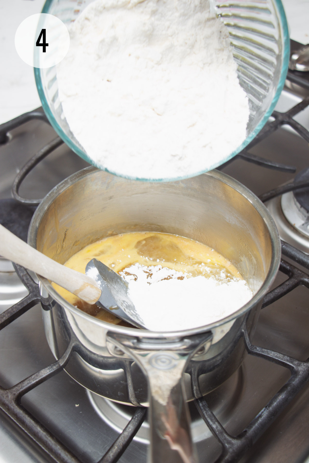 Dry ingredients being added to a saucepan with blondie bars batter mixture and being stirred with rubber spatula. 
