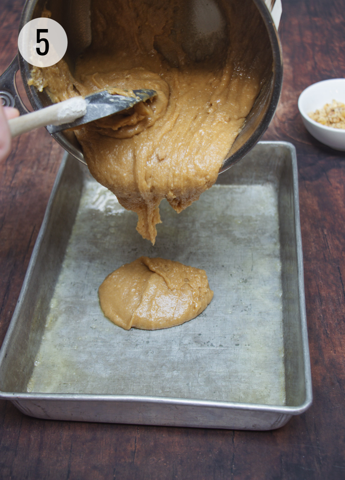 Blondie bars batter being poured and spread into a metal baking pan. 