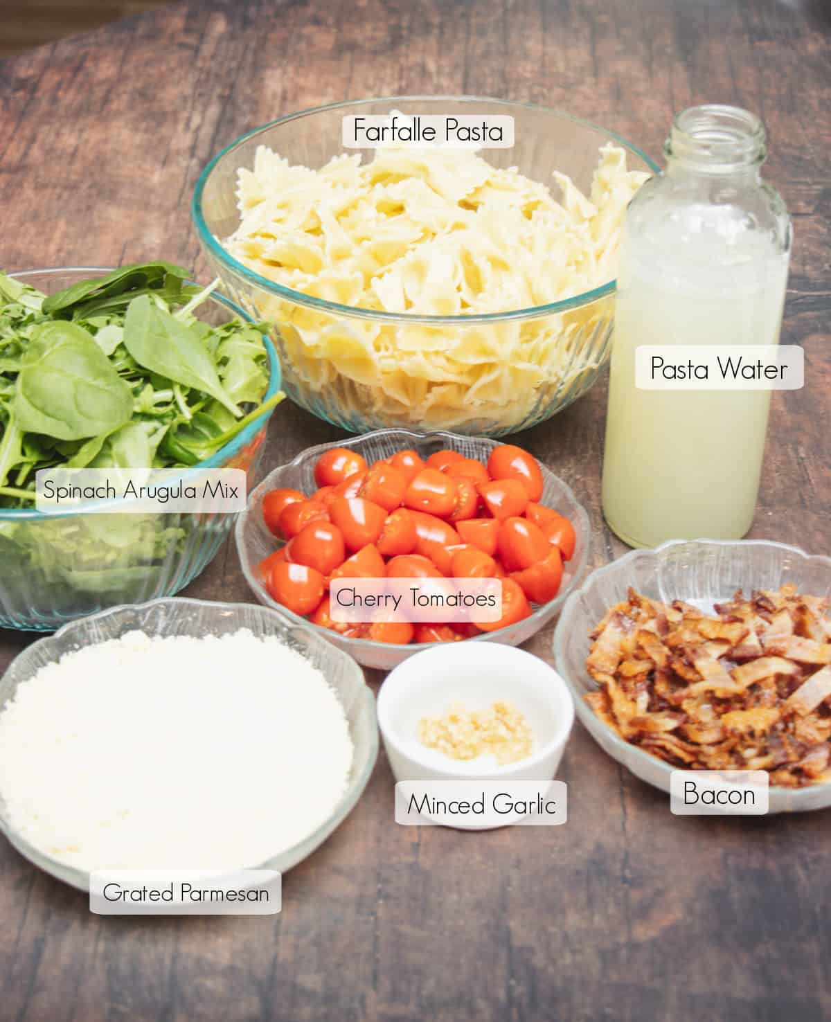 Labeled ingredients in bowls and jar to make Bacon Spinach and Tomato Pasta.