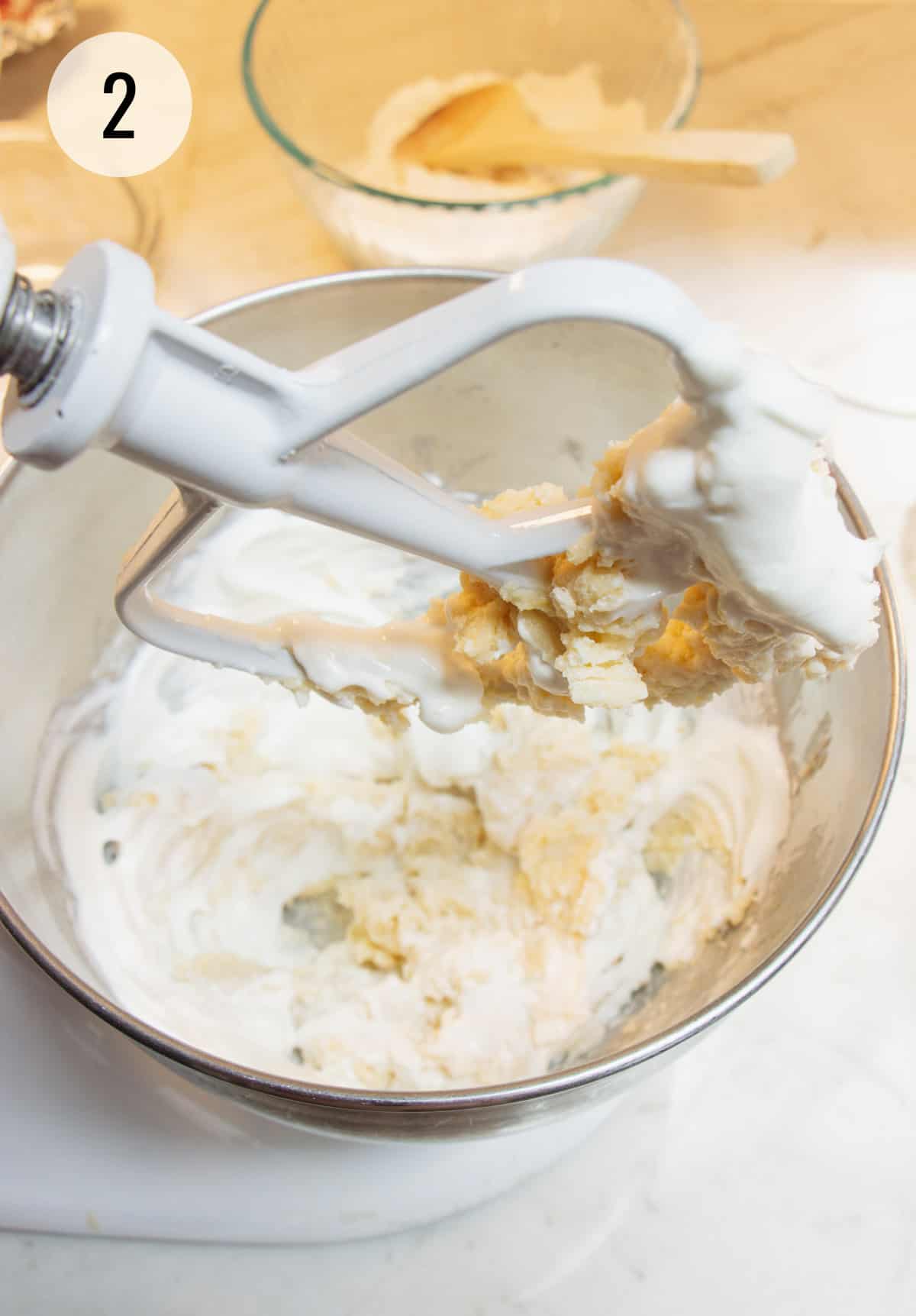 Batter mixture for lemon bread recipe in metal bowl and on paddle of stand mixer. 