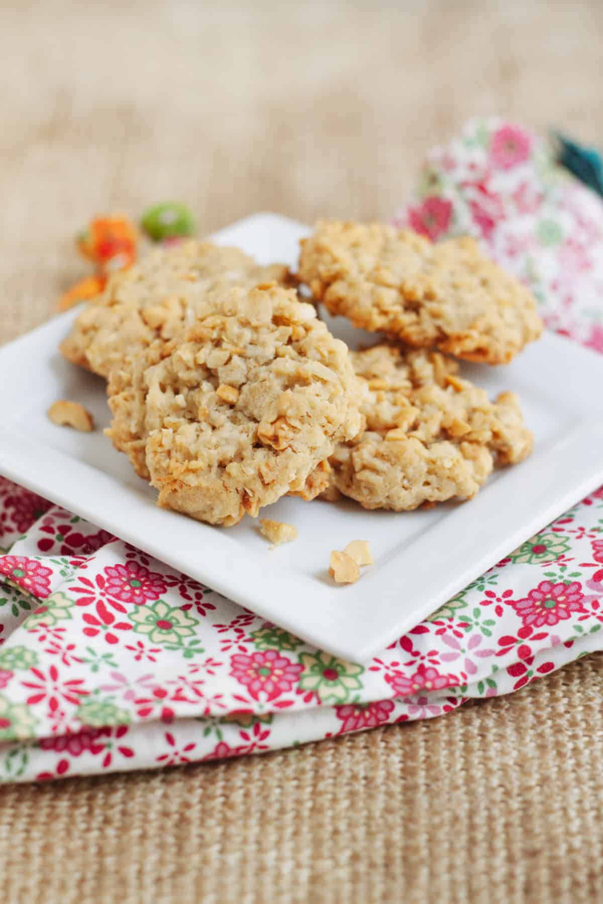 Low stack of Cracker Jack Rice Krispie Cookies on a square white plate on a pink, green and white napkin. 