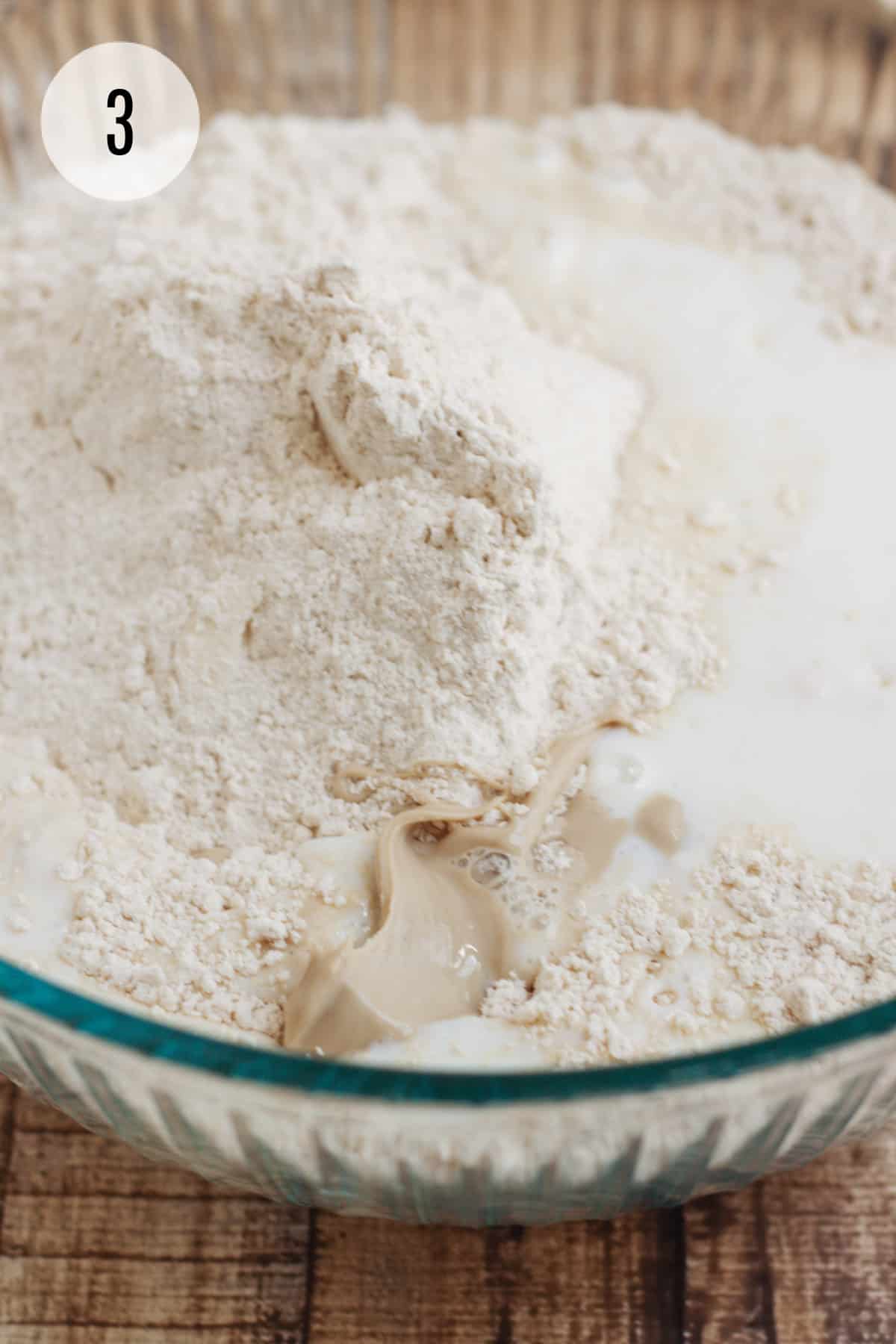 Whole Wheat biscuits flour mixture with buttermilk and yeast mixture in a glass bowl. 