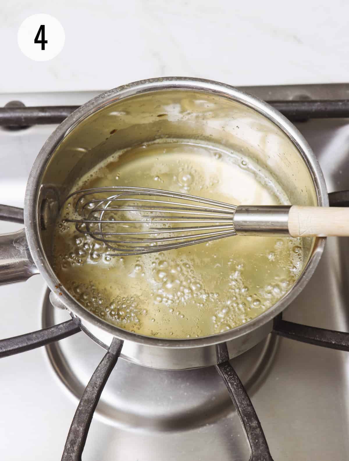 Metal sauce pan with boiling lemon simple syrup and using a whisk to stir. 