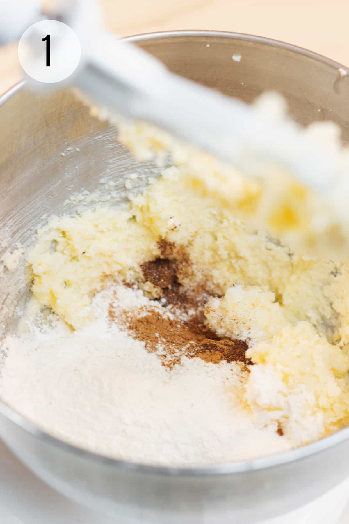 Metal mixing bowl with butter, flour and cocoa powder with stand mixer beater in upper right. 