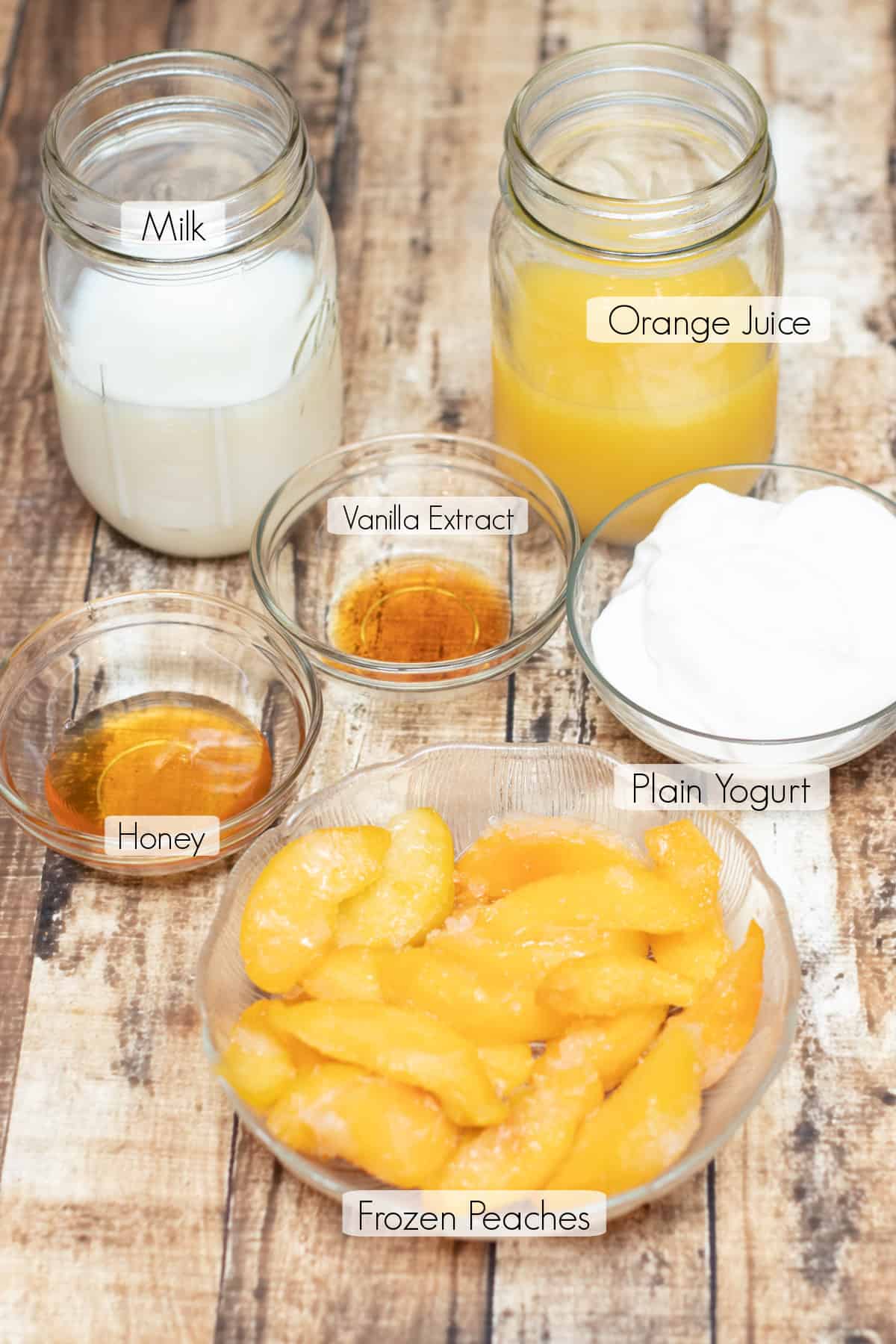 Labeled ingredients for making an orange peach smoothie.