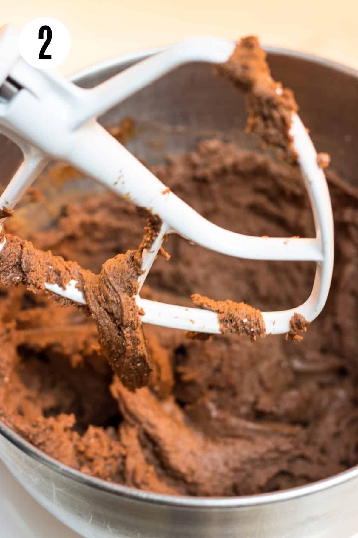 Chocolate cookie dough in a bowl and on white beater for mixer. 
