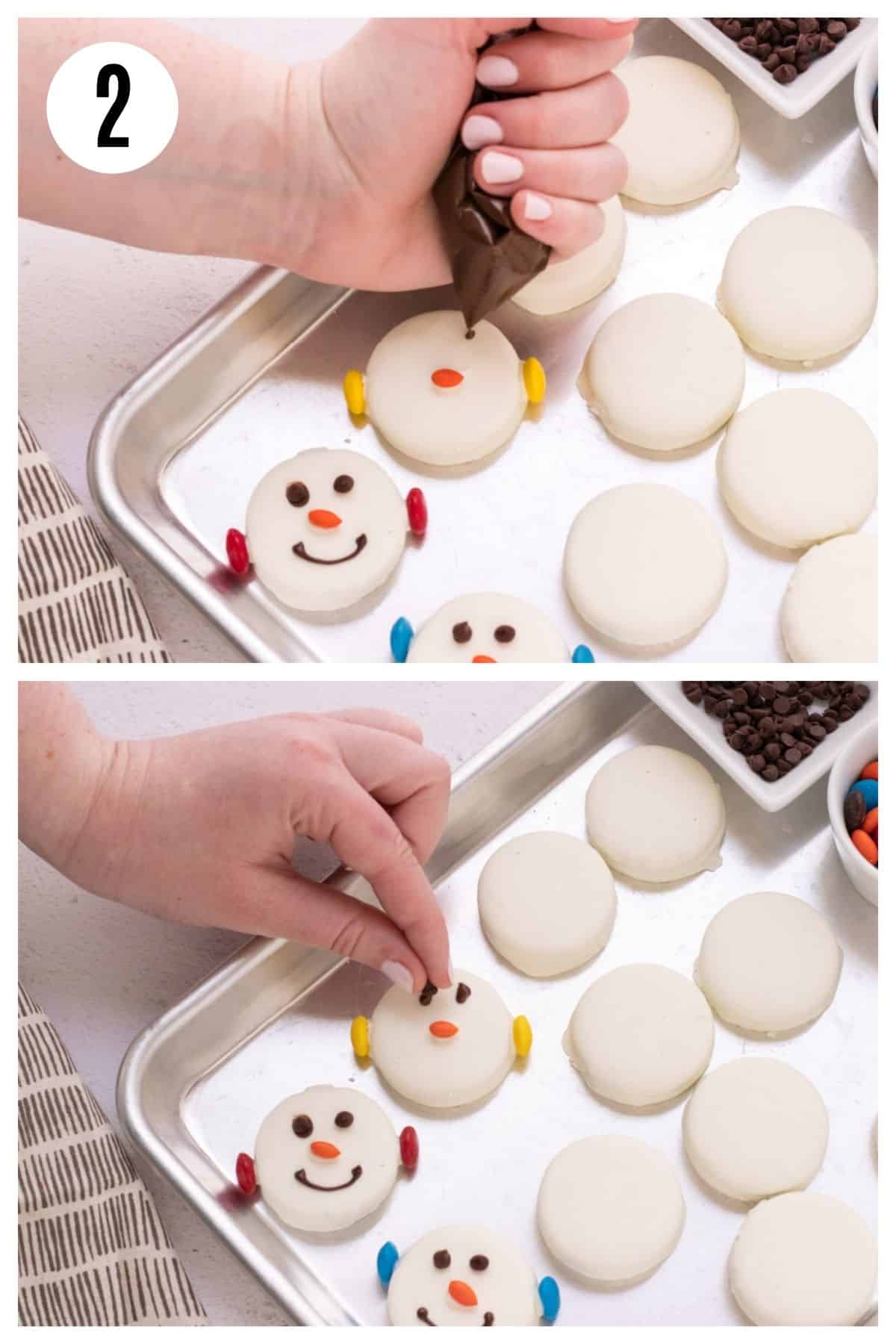 Hands squeezing melted milk chocolate onto white chocolate covered Oreo cookie and then mini chocolate chips being added to make eyes for snowman face. 
